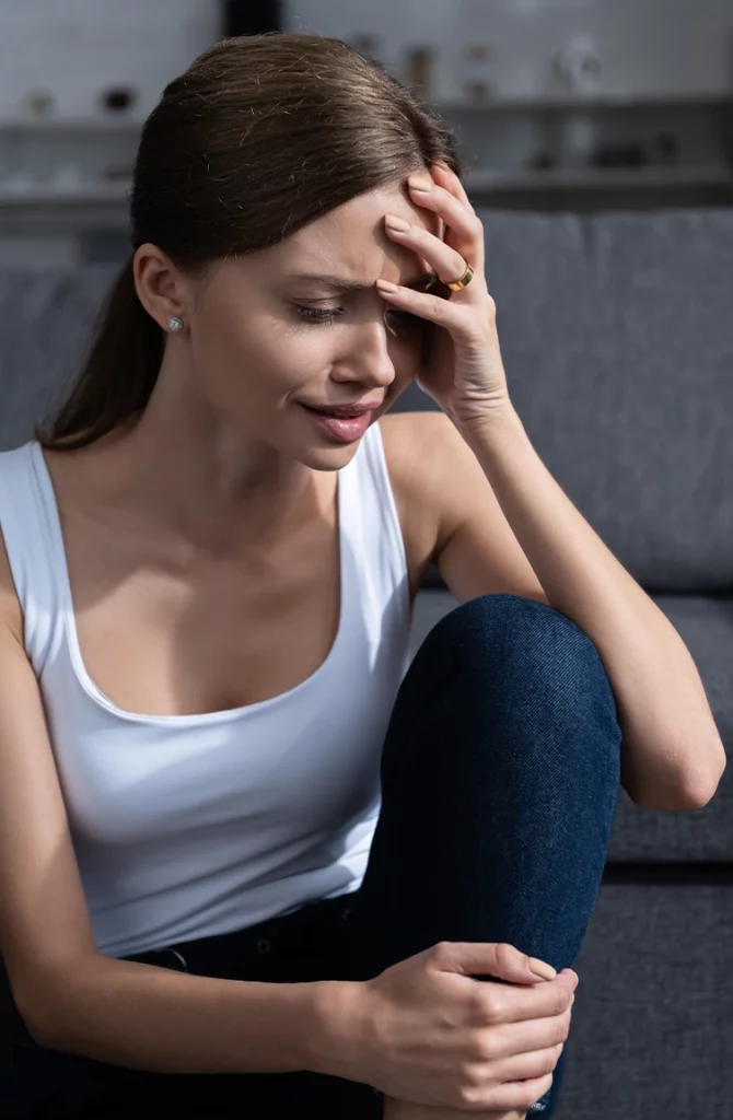 woman holding head in her hand sitting down with a migraine