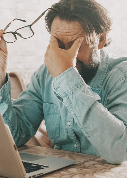 older man in green shirt in pain because of a migraine.